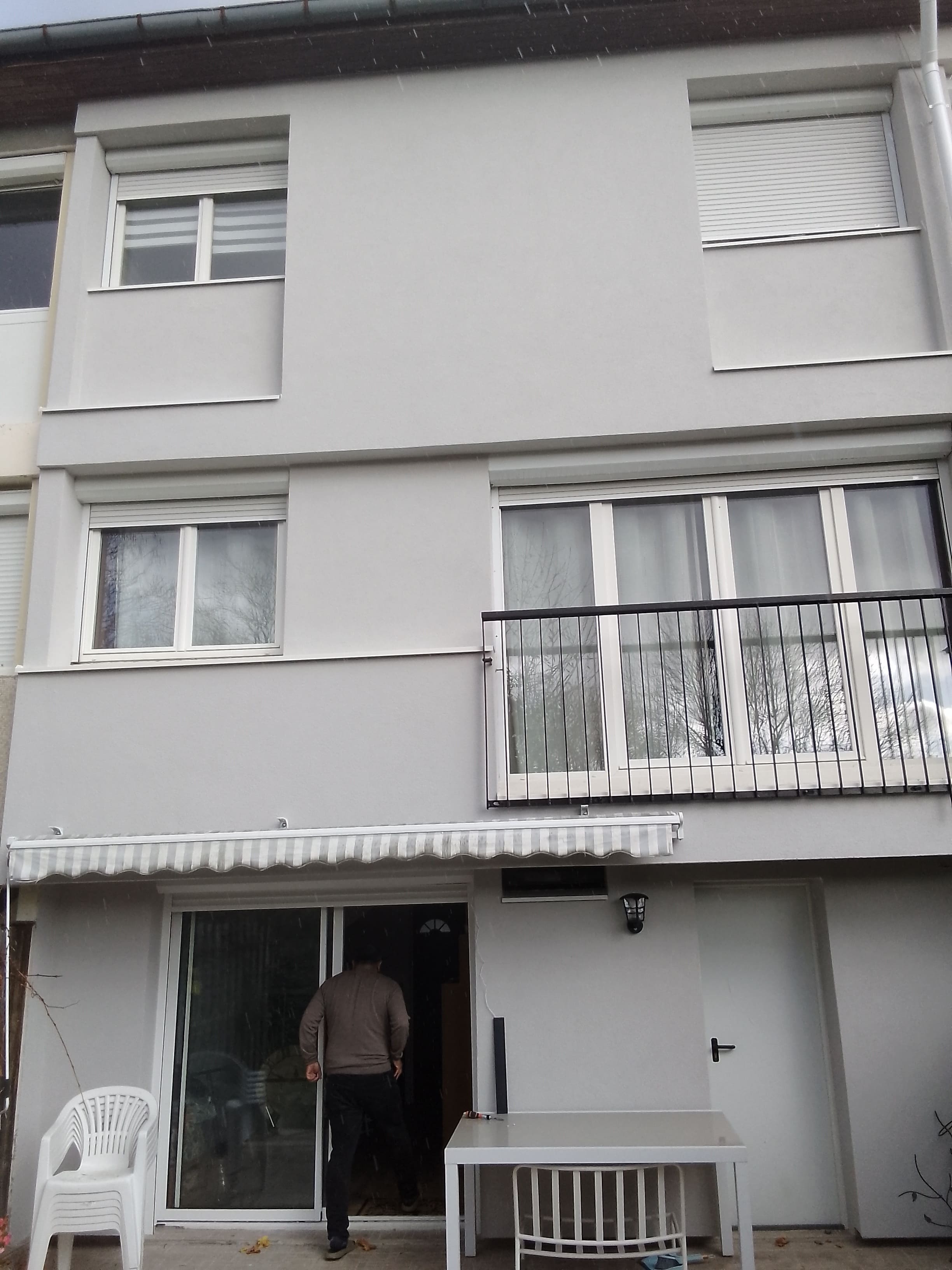Façade arrière après ITE rue de Bellevue Pontault-Combault (77340) — enduit gris clair uniforme du rez-de-chaussée à la sous-toiture, propriétaire sur le seuil — Mira Façade
