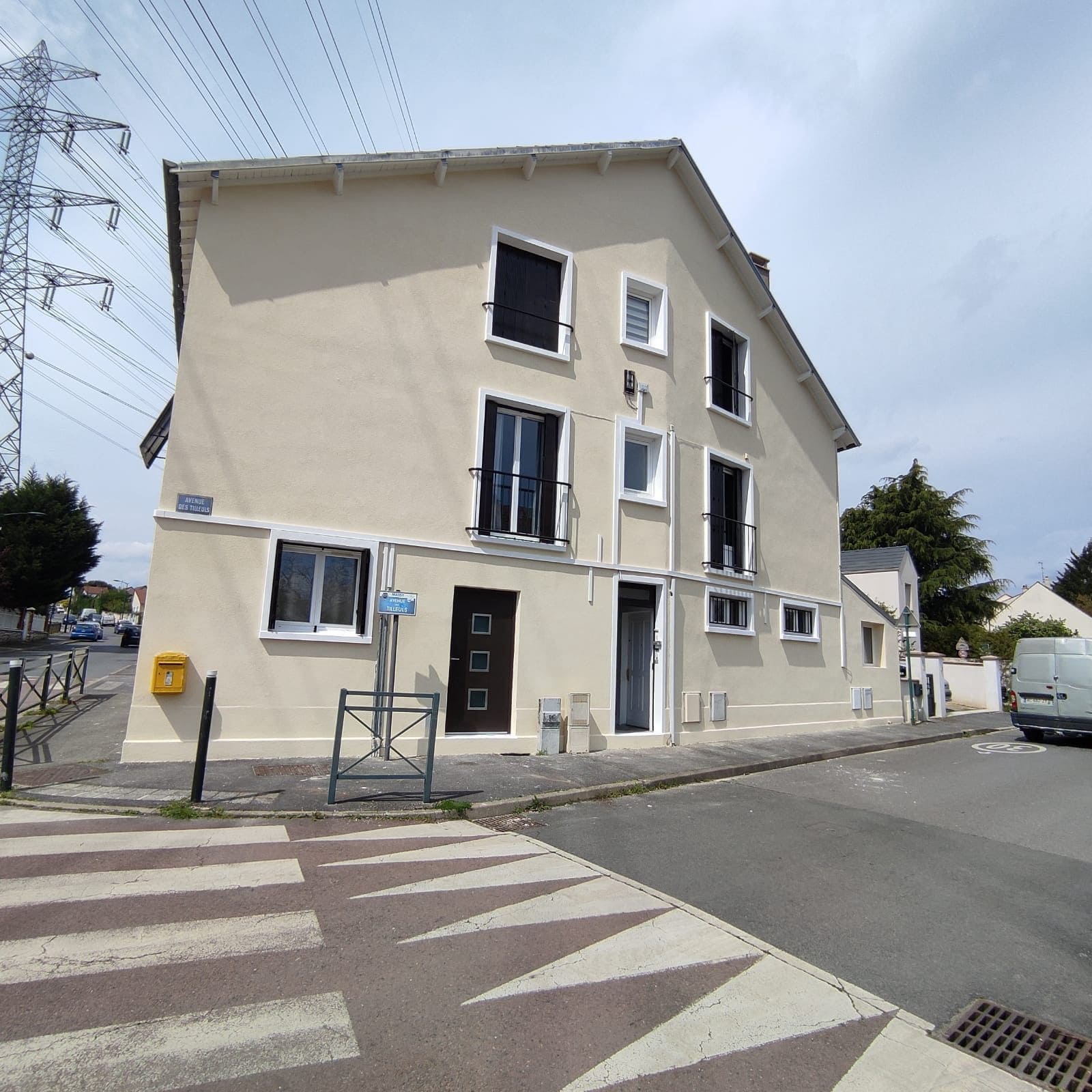 Façade principale après ITE à Massy-Palaiseau (91) — enduit gratté ton beige pierre, encadrements blancs soignés, angle de rue, maison individuelle R+2 — Mira Façade