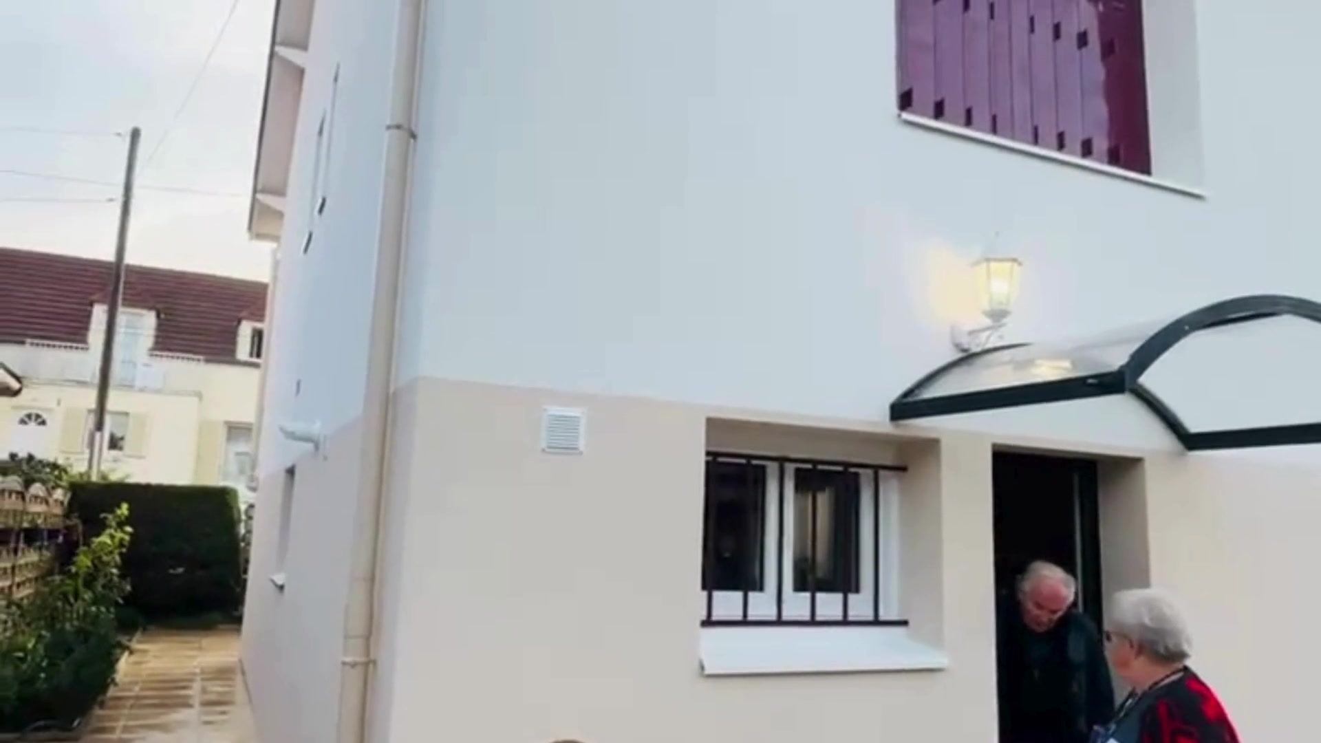 Façade principale après réception ITE à Chelles (77) - propriétaires présents, enduit deux tons blanc et gris soubassement, maison R+1 transformée
