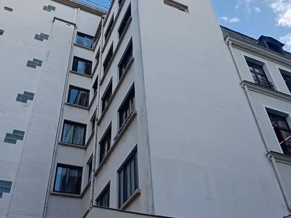 Angle de la façade côté cour, vue depuis la droite, montrant le bâtiment mitoyen avec ses balcons