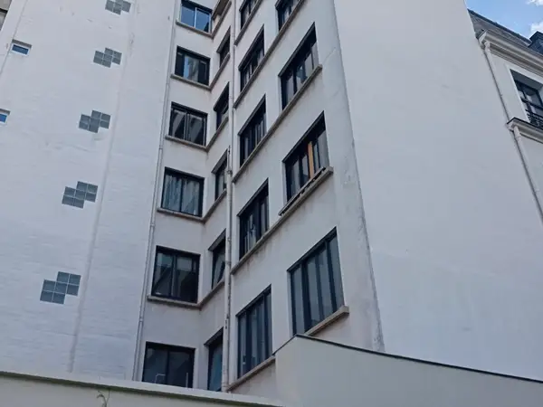 Angle de la façade côté cour, vue depuis la gauche, montrant la mitoyenneté avec le bâtiment voisin
