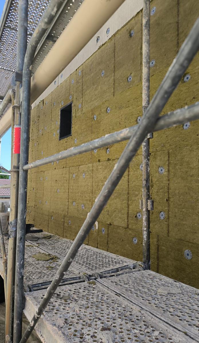 Isolant posé sur la façade d'un pavillon depuis l'échafaudage, chantier ITE à Goussainville (95)